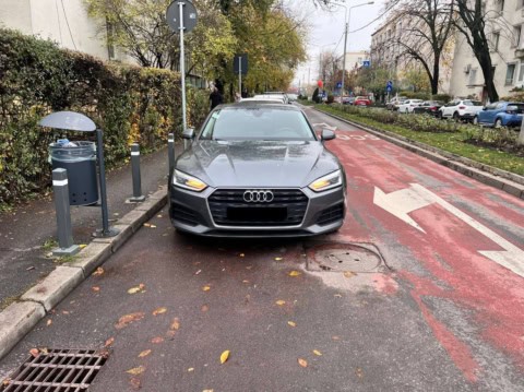 Mașină Audi pe stradă în condiții de ploaie, parcat pe pista de biciclete, în oraș.