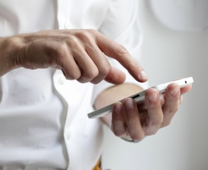 Persoană folosind telefonul mobil pentru controlul unui dispozitiv inteligent.